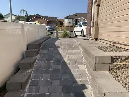 Anderson Project after: grey paver steps and a raised block planter along the house