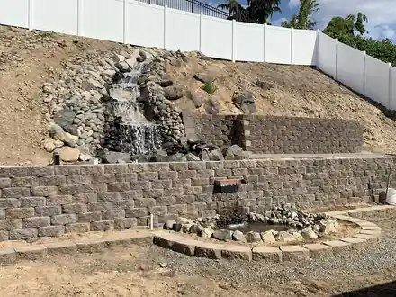 Scott Project during the build: the waterfall channel and pond basin taking shape below the wall