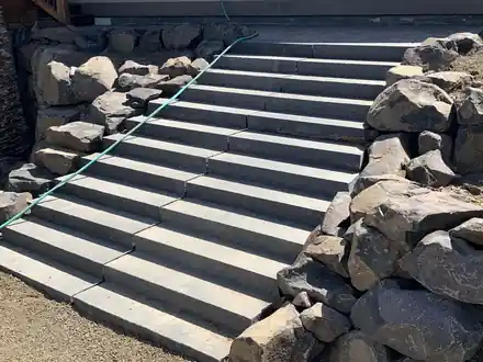 A long run of block stairs set between large basalt boulders on a slope